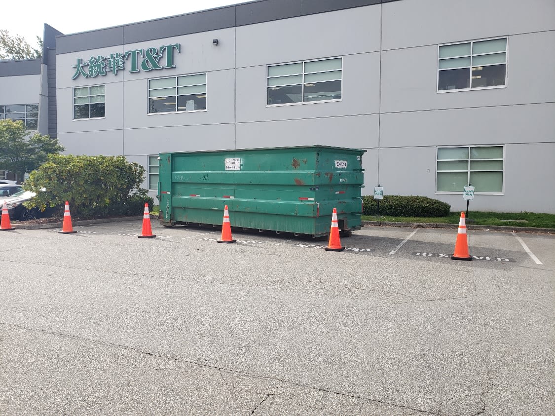 Green roll-off bin outside a commercial building